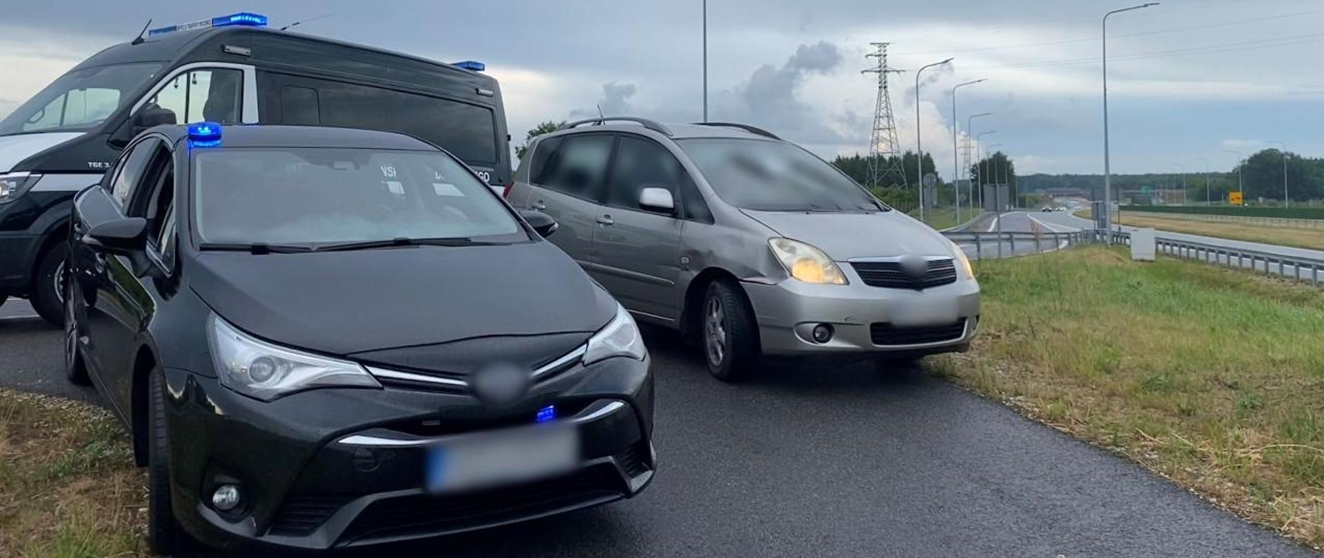 Na pierwszym planie (od lewej): nieoznakowany radiowóz mazowieckiej Inspekcji Transportu Drogowego z włączonymi niebieskimi światłami uprzywilejowania w ruchu drogowym i zatrzymany do kontroli samochód osobowy. W tle: za zatrzymaną osobówką stoi oznakowany furgon ITD. Ekspresową „siódemką” przejeżdżają pojazdy w kierunku z Warszawy do Radomia. 