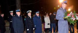 Funkcjonariusze służb mundurowych składają wieniec pod pomnikiem. 