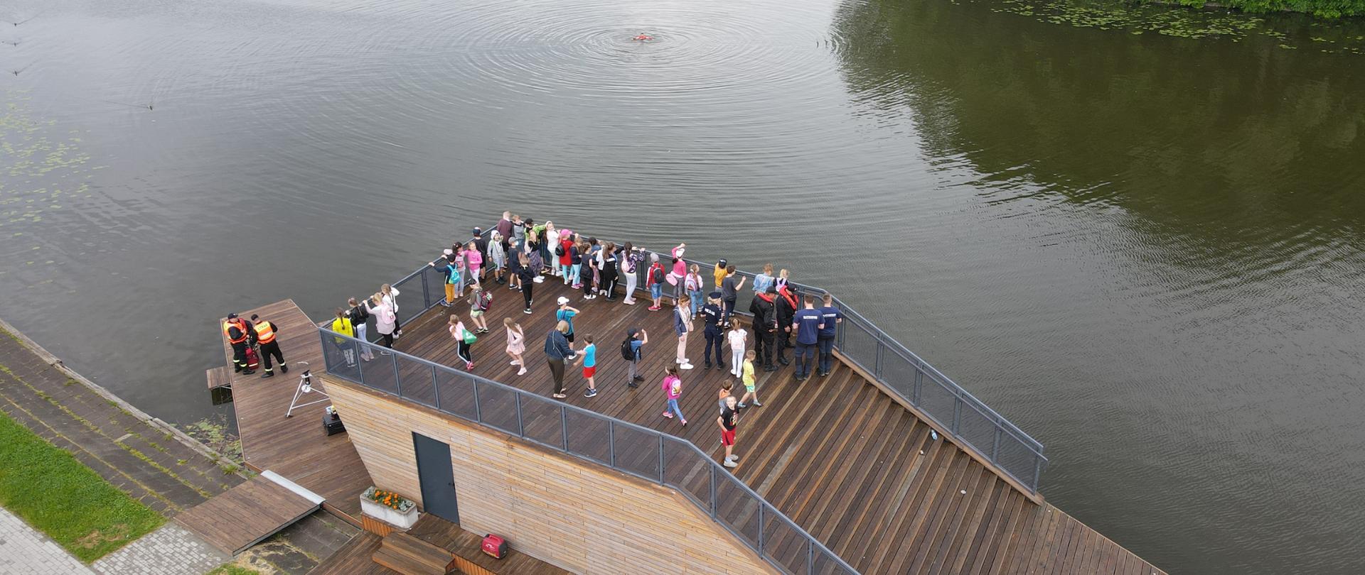 Na zdjęciu widoczna grupa dzieci oraz strażacy podczas pokazu sprzętu ratowniczego.