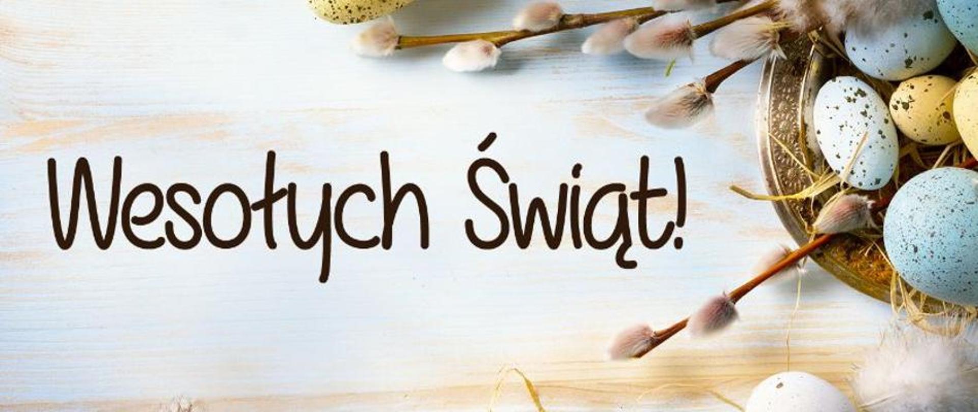 Na jasnym tle napis Wesołych Świąt. Po prawej stronie gałązki oraz jajka - symbole Wielkanocy