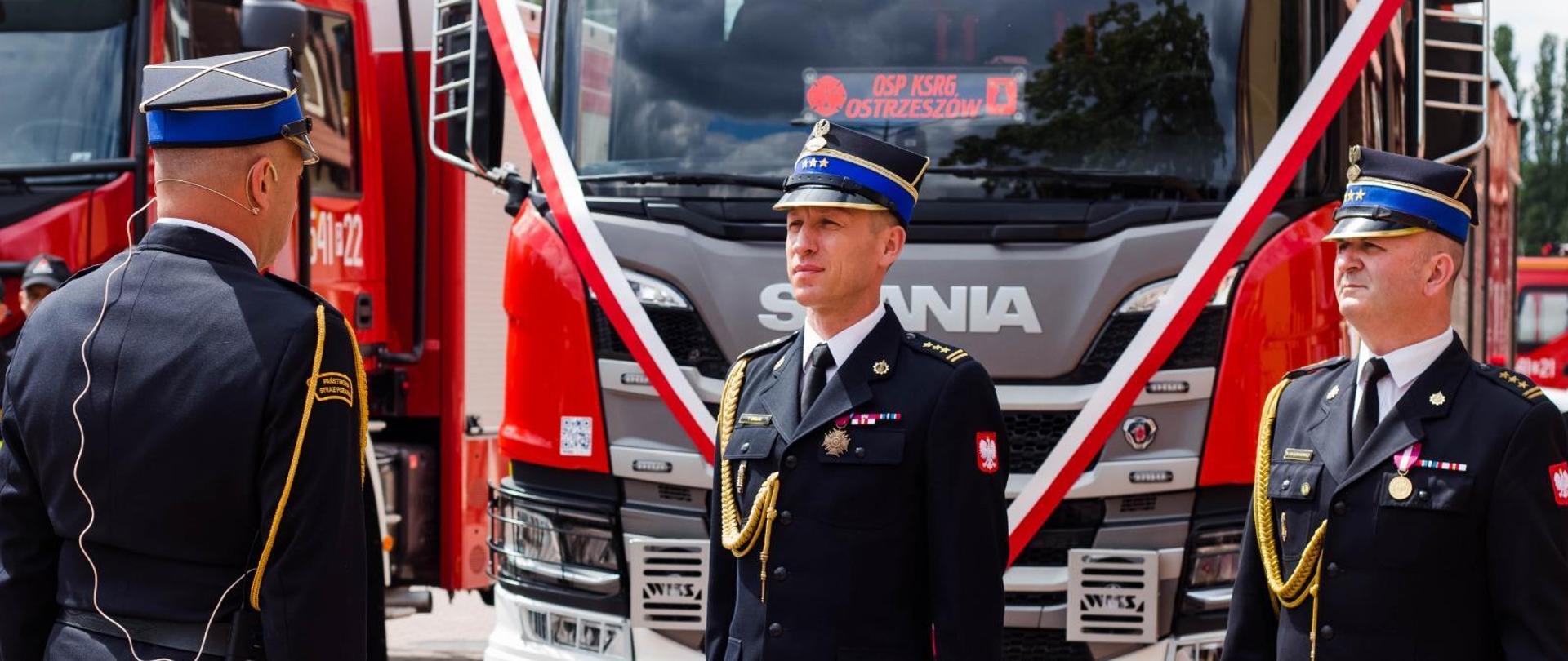 rozpoczęcie uroczystości, składanie meldunku zastępcy wielkopolskiego komendanta wojewódzkiego PSP , w tle czerwony wóz strażacki