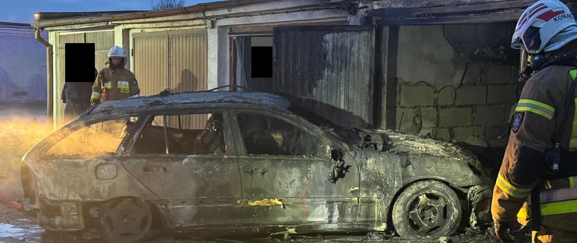 Spalony samochód na zewnątrz, w pobliżu strażacy