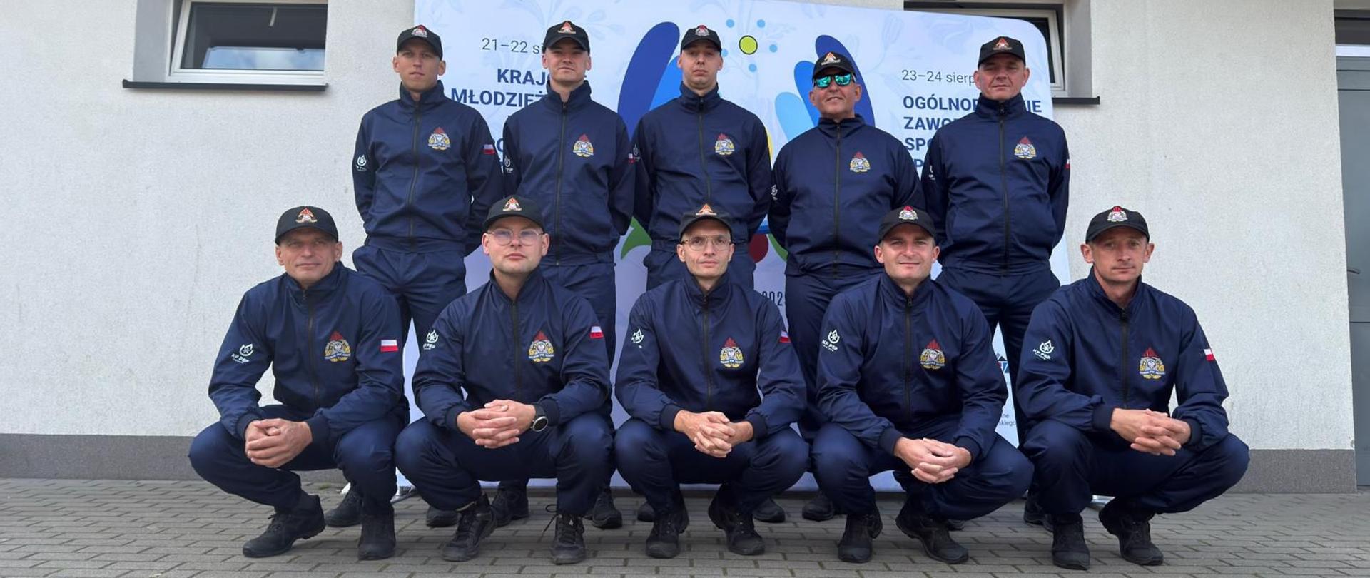 grupa strażaków na tle ścianki pozujący do zdjęcia