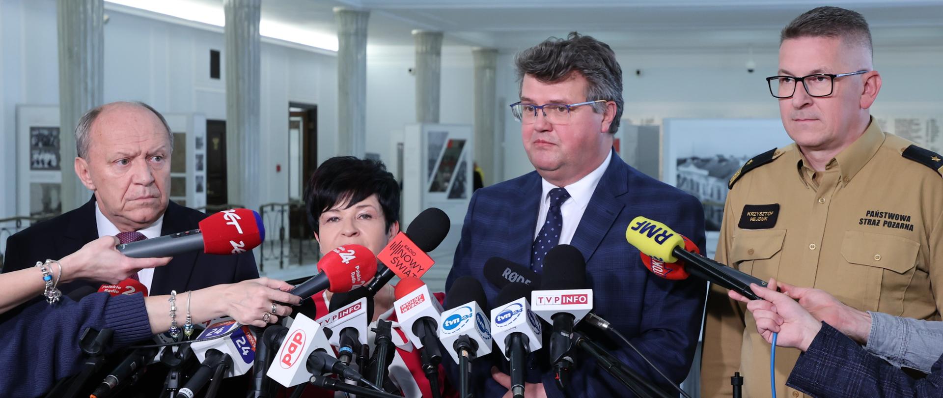 Zdjęcie przedstawia uczestników konferencji prasowej, widać wiele mikrofonów z logami stacji.