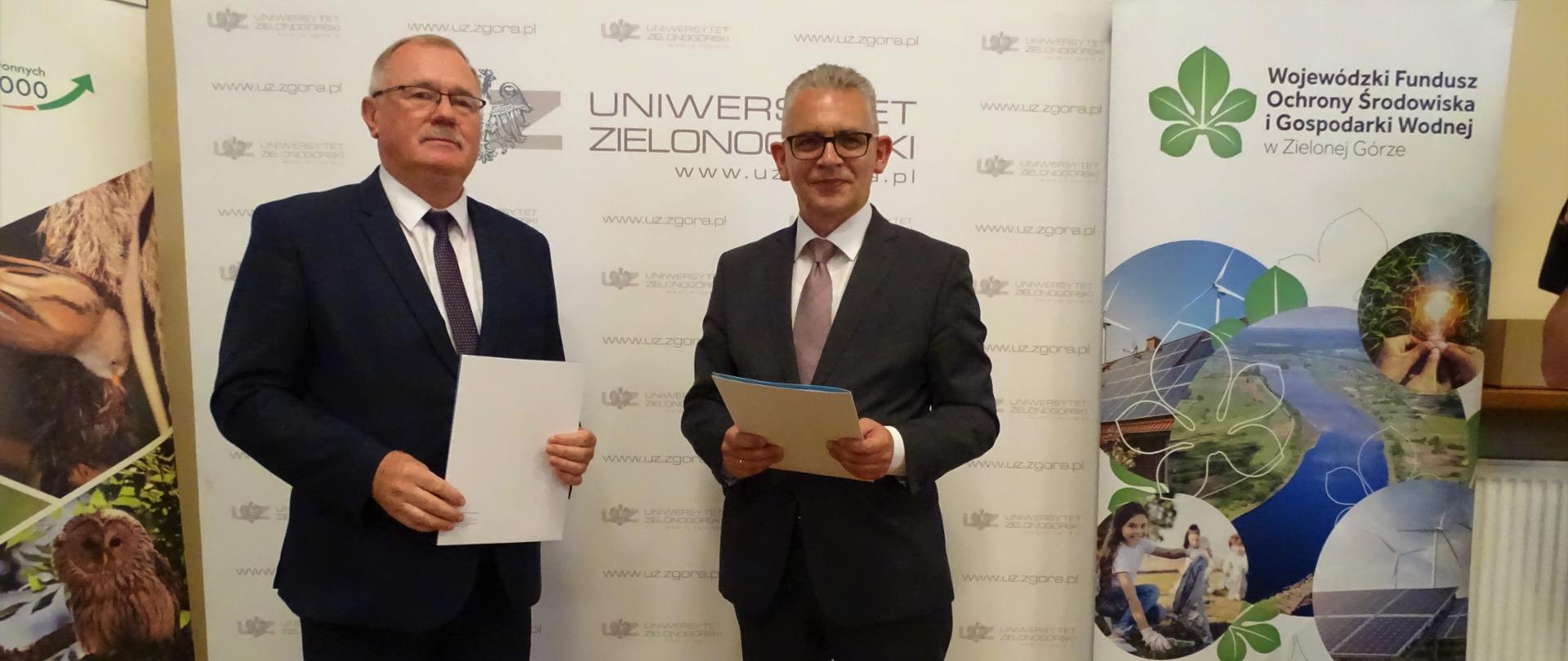 Józef Kruczkowski- Regionalny Dyrektor Ochrony Środowiska i prof. dr hab. Wojciech Strzyżewski trzymają list intencyjny, pozując na tle banneru Uniwersytetu Zielonogórskiego.