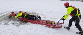 Dzień. Na zamarzniętym akwenie, ratownicy w jaskrawych strojach i czerwonych kaskach wydobywają osobę z przerębla. Jeden z ratowników leży na specjalnych saniach lodowych i podaje rękę poszkodowanemu, podczas gdy drugi ciągnie sanie liną z brzegu. Cała scena rozgrywa się w zimowym.