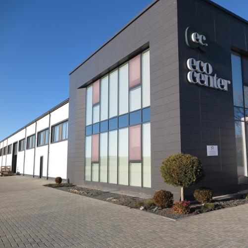 Budynek biurowy z napisem EcoCenter. Na budynku wisi niewielka tabliczka z logo Polskiej pomocy