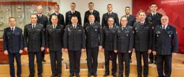 szesnastu strażaków pozujących do zdjęcia stoją w dwóch rzędach w sali konferencyjnej