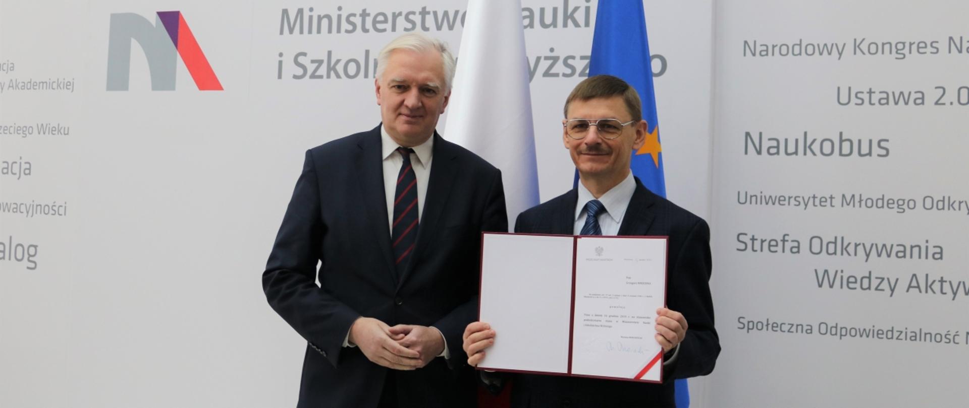 Powołanie prof. Grzegorza Wrochny na stanowisko podsekretarza stanu w MNiSW. Prof. Wrochna i minister Gowin stoją na tle ściany z logiem MNiSW i flag Polski i UE.