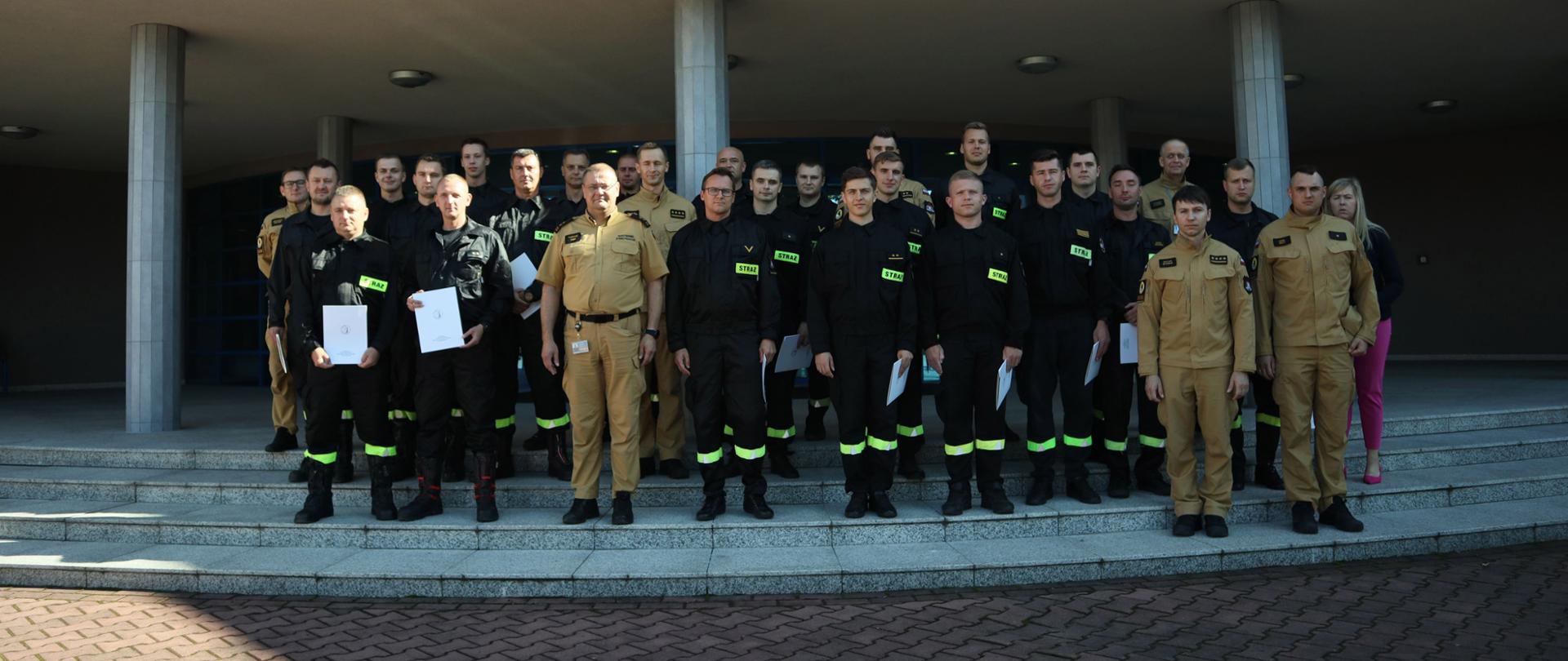 Grupowe zdjęcie funkcjonariuszy PSP będących uczestnikami (23 osoby) szkolenia w towarzystwie Zastępcy Komendanta Centralnej Szkoły PSP, czterech funkcjonariuszy CS PSP oraz kobiety