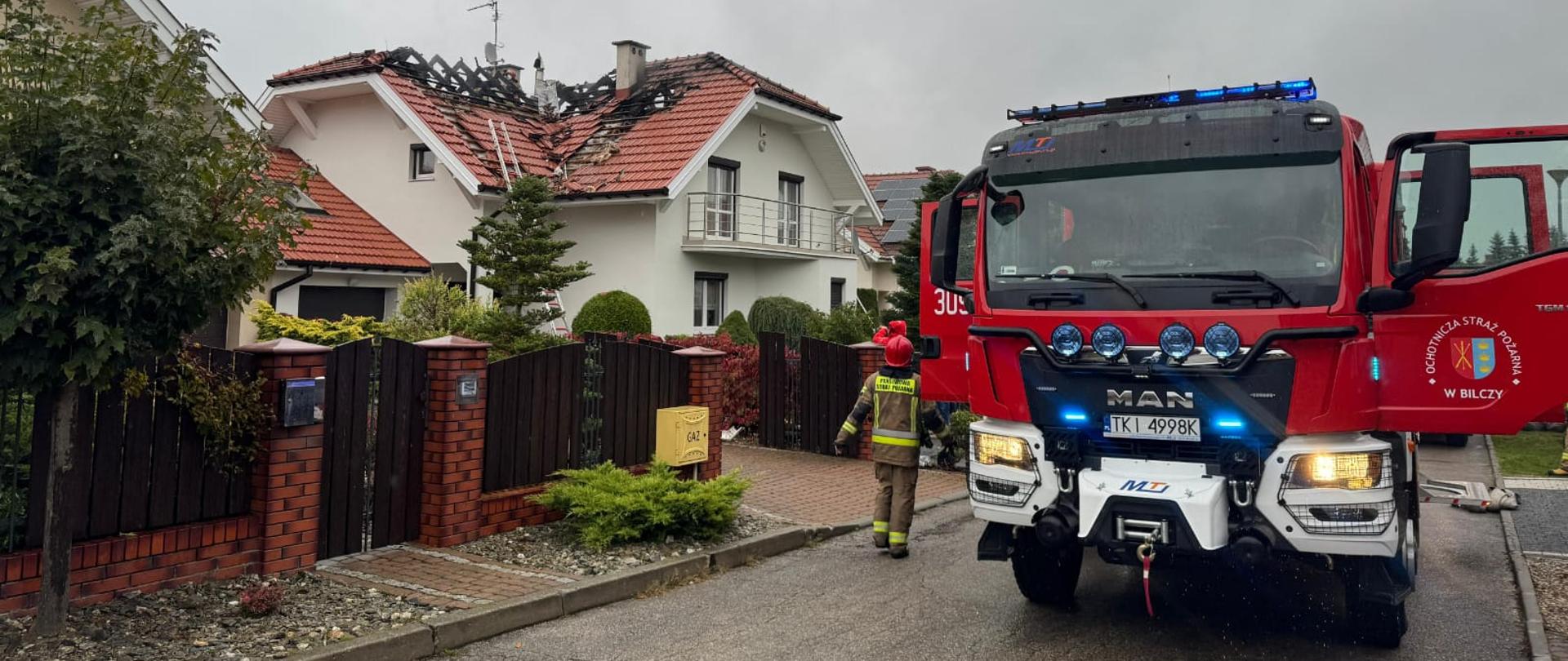 Na zdjęciu, po lewej zniszczony w pożarze dom, a po prawej stoi samochód gaśniczy.