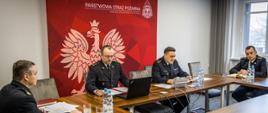 Zdjęcie przedstawia Opolskiego Komendanta Wojewódzkiego PSP st. bryg. Krzysztofa Kędryka, Zastępcę Opolskiego Komendanta Wojewódzkiego PSP st. bryg. Arkadiusza Kuśmierskiego i Zastępcę Opolskiego Komendanta Wojewódzkiego PSP bryg. Wojciecha Nawarę podczas wideokonferencji zorganizowanej w ramach narady rocznej kadry kierowniczej PSP województwa opolskiego. Prelegent bryg. Michał Zawiślak naczelnik wydziału kontrolno - rozpoznawczego KW PSP w Opolu.