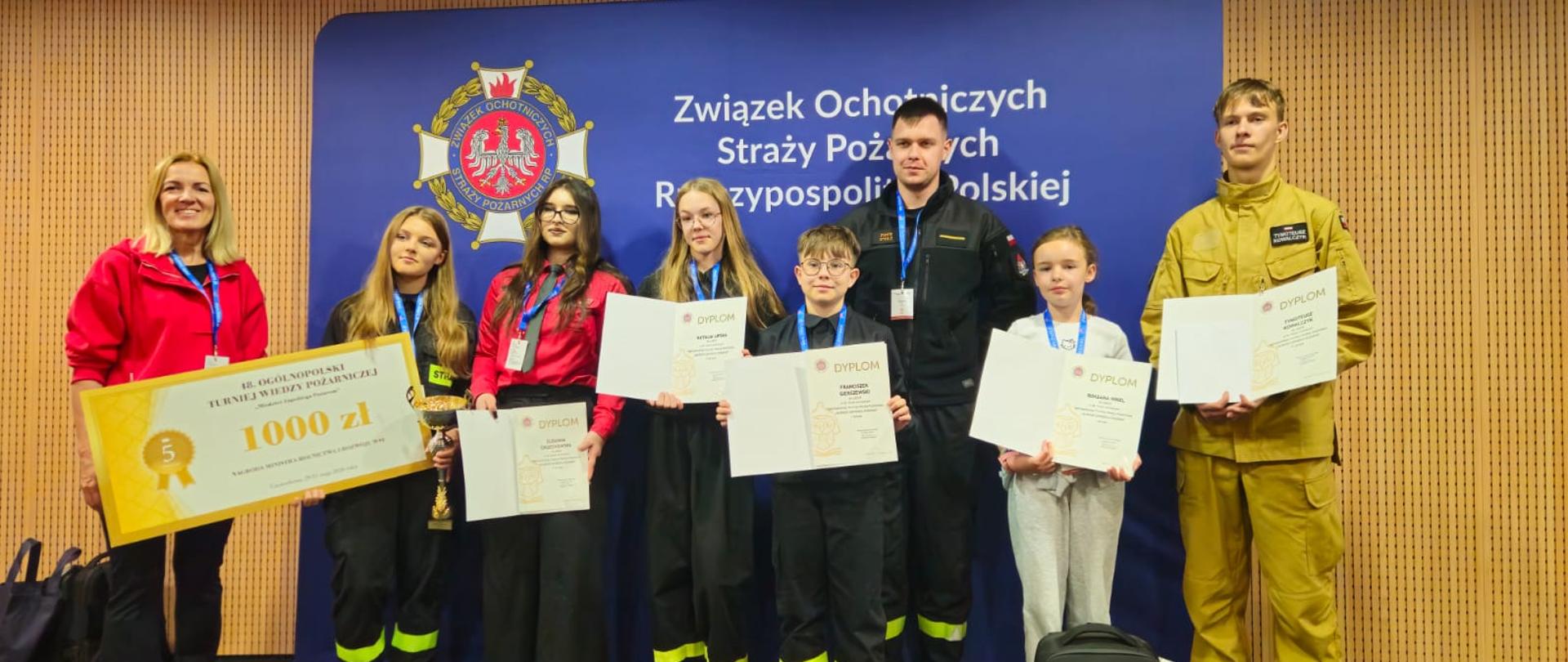 Zdjęcie przedstawia uczestników turnieju finałowego wiedzy pożarniczej wraz z opiekunami. 