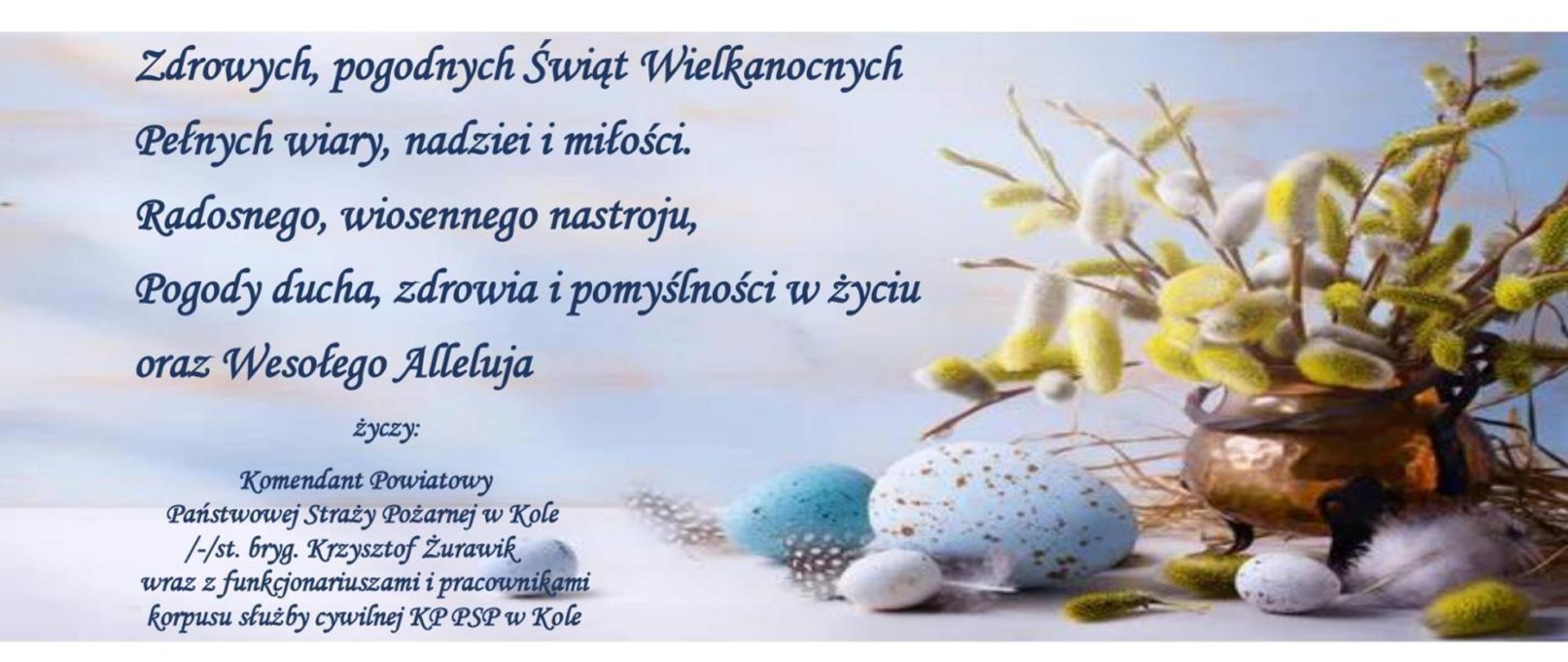 Zdjęcie przedstawia życzenia wielkanocne Komendanta Powiatowego PSP w Kole na niebieskim tle z jajkami, baziami w wazonie