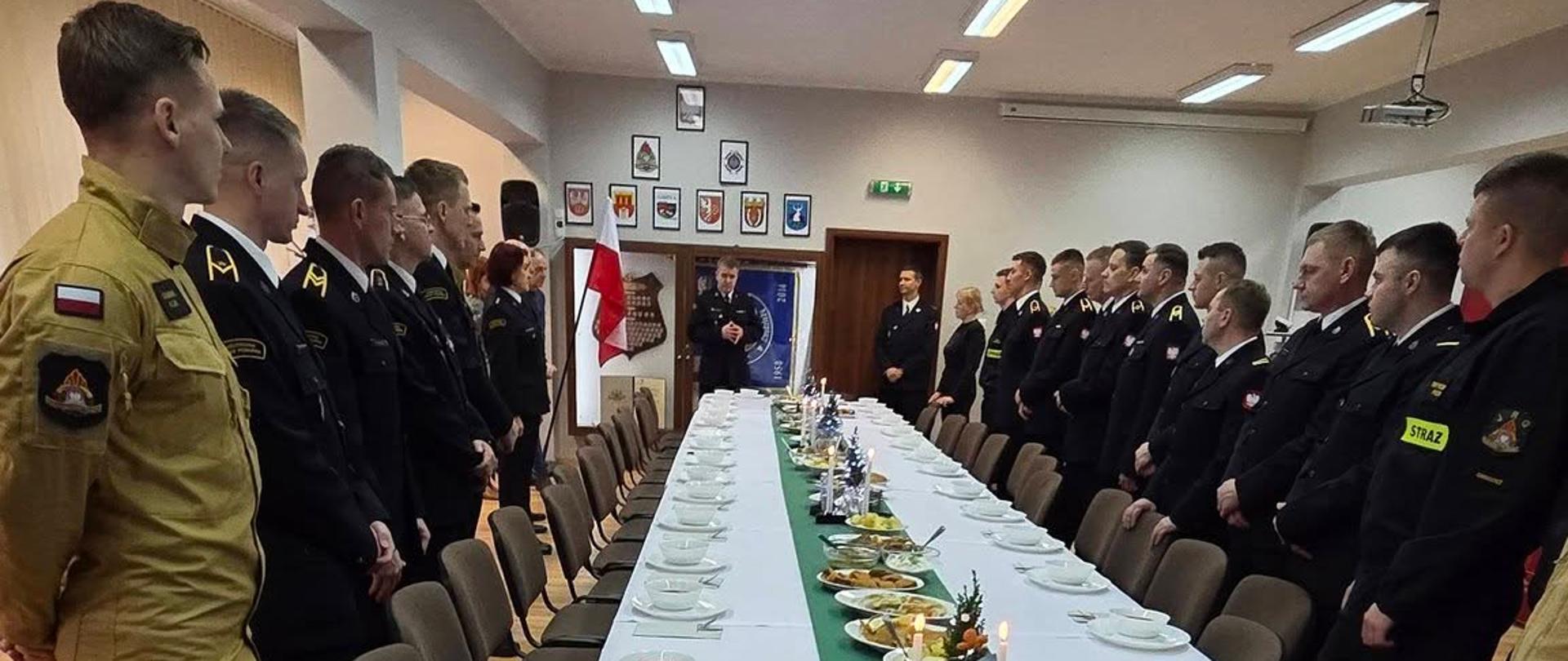 Zdjęcie przedstawia strażaków podczas uroczystego spotkania Wigilijnego w KP PSP w Chodzieży. W tle świetlica komendy. 