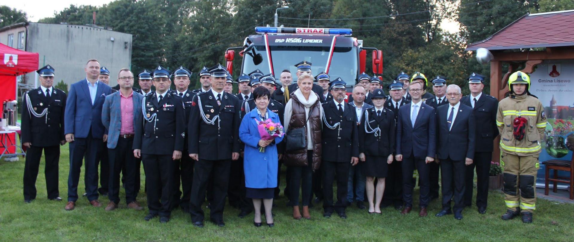 Na zdjęciu znajdują się zaproszeni goście oraz druhowie podczas wspólnego zdjęcia po uroczystym przekazaniu pojazdu, uczestnicy znajdują się na tle pojazdu.