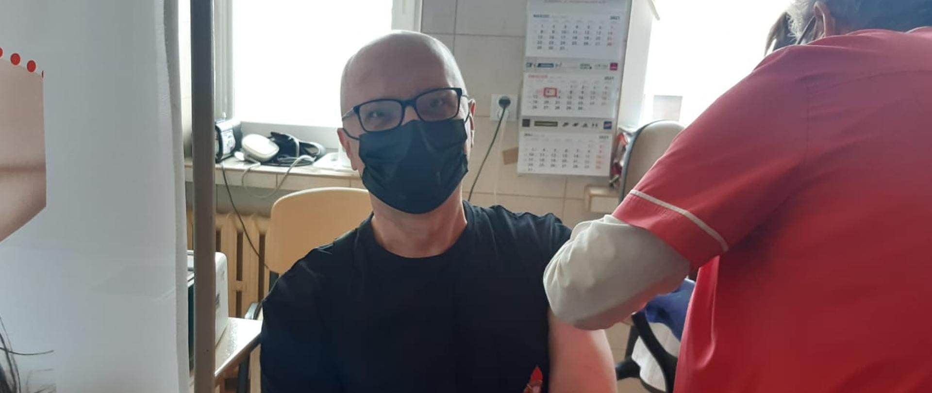 Na zdjęciu strażak podczas szczepienia przeciwko COVID-19