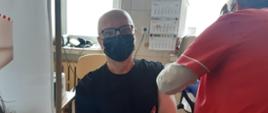 Na zdjęciu strażak podczas szczepienia przeciwko COVID-19