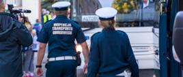 Inspektorzy kontrolują autobus szkolny w Lesznowoli. Przebieg kontroli obserwują dziennikarze uczestniczący w briefingu.