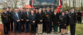 Grupa osób stojąca przed pojazdem straży pożarnej. 