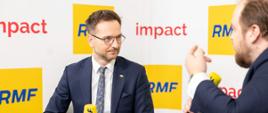 Minister rozwoju i technologii Waldemar Buda udzielający wywiadu podczas Impact'22, za plecami ministra baner z Impact'22 i logo RMF FM 