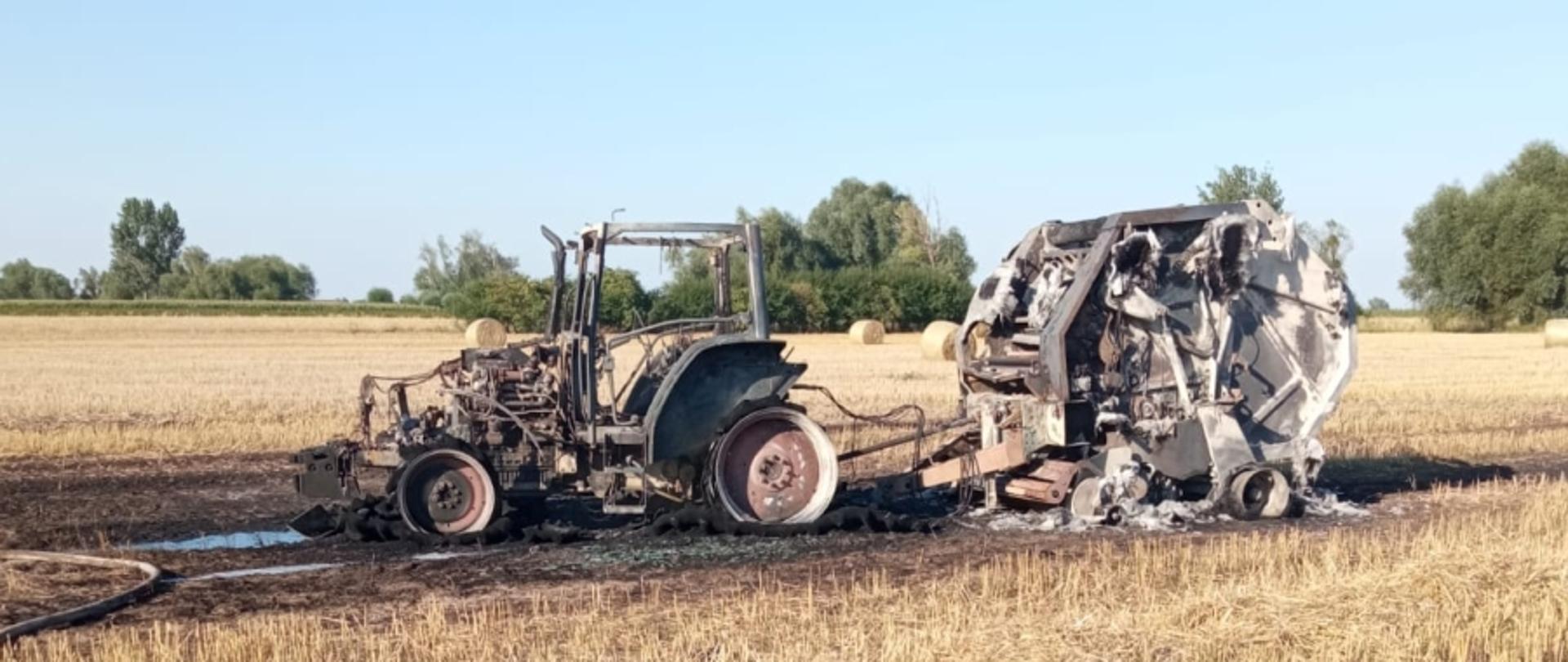 Na miejscu widoczny spalony ciągnik rolniczy sprzężony z prasą belującą, stojący na rżysku.