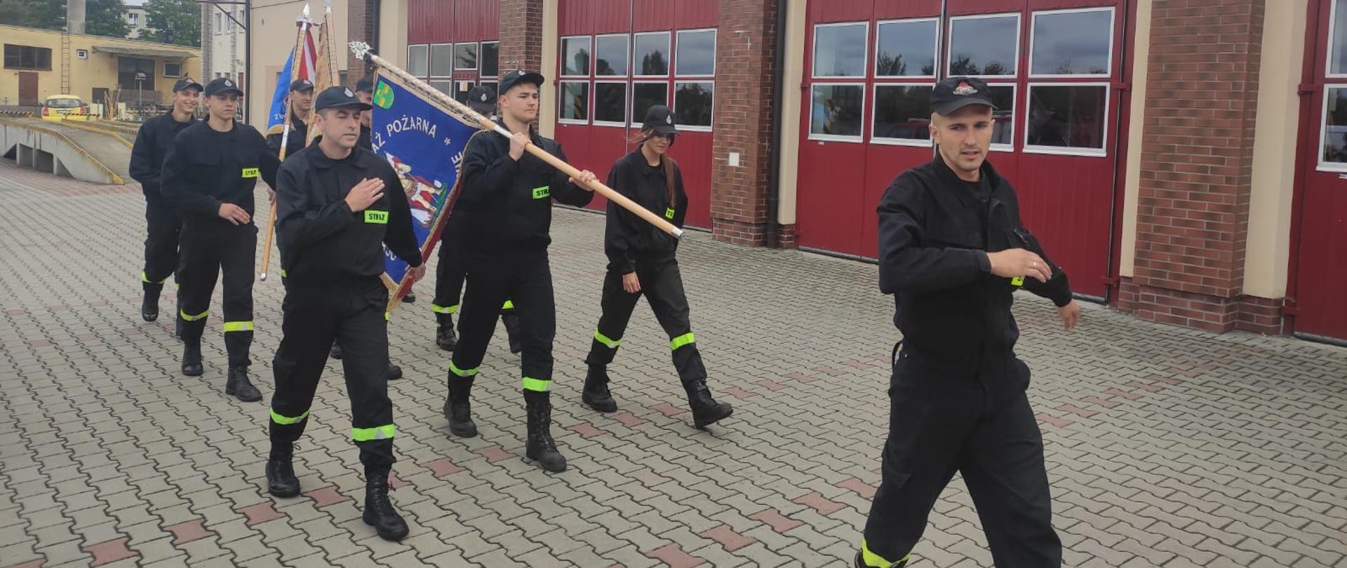 Strażacy z sztandarami ćwiczą prawidłowe zachowanie podczas musztry