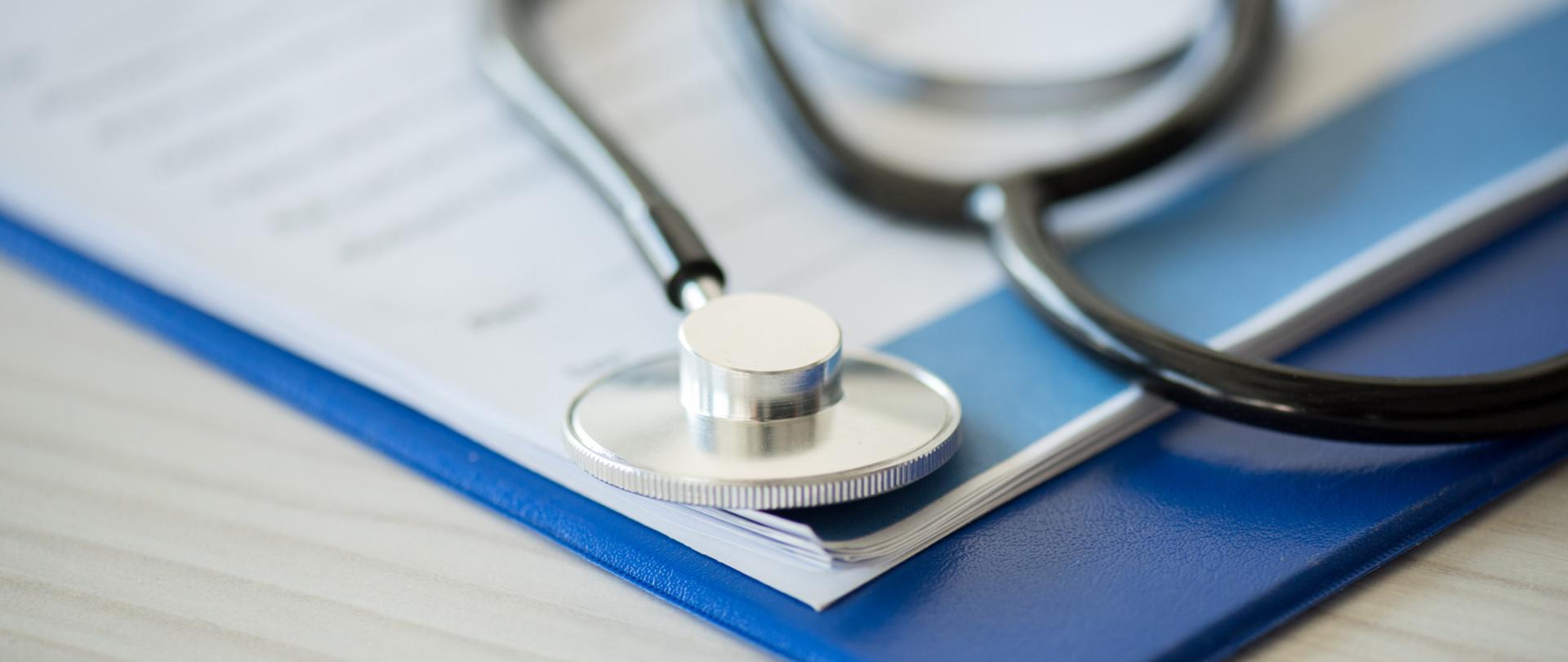 Na zdjęciu jest stetoskop. W tle widać notatnik.