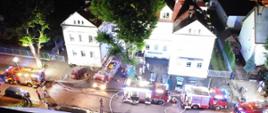 Samochody strażackie przed budynkiem w którym zaistniał pożar