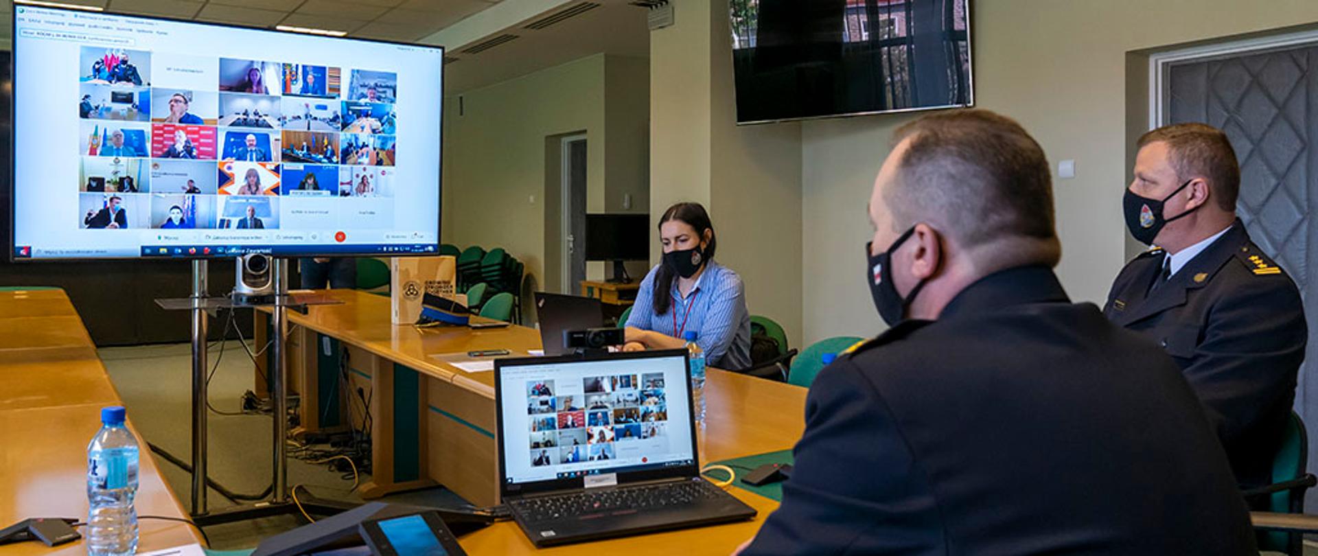 Zastępca Komendanta Głównego PSP nadbrygadier Adam Konieczny podczas wideokonferencji. W tle widoczny terminal wideokonferencyjny