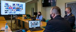 Zastępca Komendanta Głównego PSP nadbrygadier Adam Konieczny podczas wideokonferencji. W tle widoczny terminal wideokonferencyjny