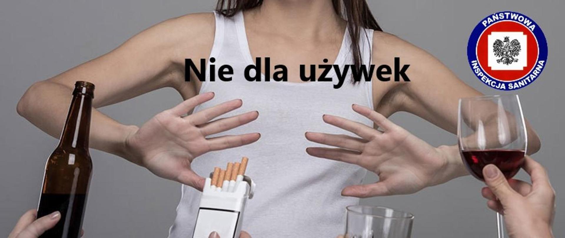 Kobieta w białej podkoszulce w długich czarnych włosach, która rękoma pokazuje ze nie będzie spożywać używek, poniżej po prawej stronie butelka z piwem, obok paczka papierosów, szklanka oraz kieliszek z winem. Na środku napis Nie dla używek, a po prawej stronie u góry logo Inspekcji Sanitarnej
