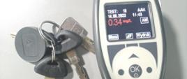 Inspekcyjny alkomat z wynikiem pomiaru trzeźwości kierowcy (0,34 mg/l) i leżące obok urządzenia kluczyki od ciężarówki.