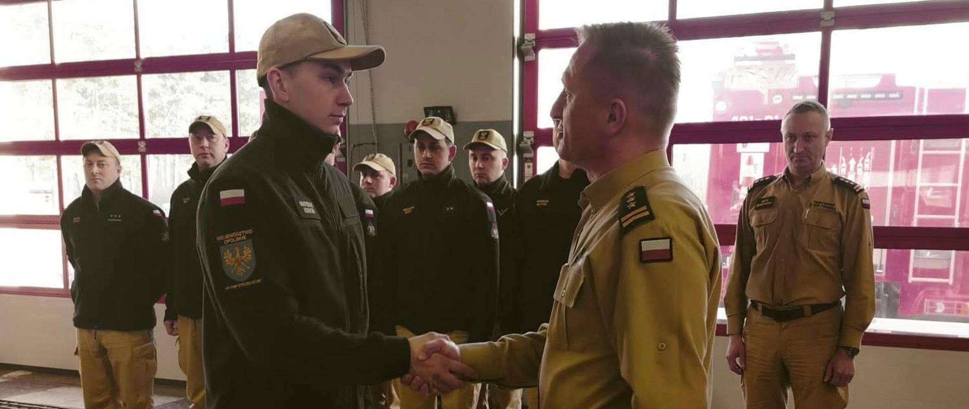 Na zdjęciu widać składanie gratulacji przez Komendanta Powiatowego PSP strażakowi Mateuszowi Izbickiemu.