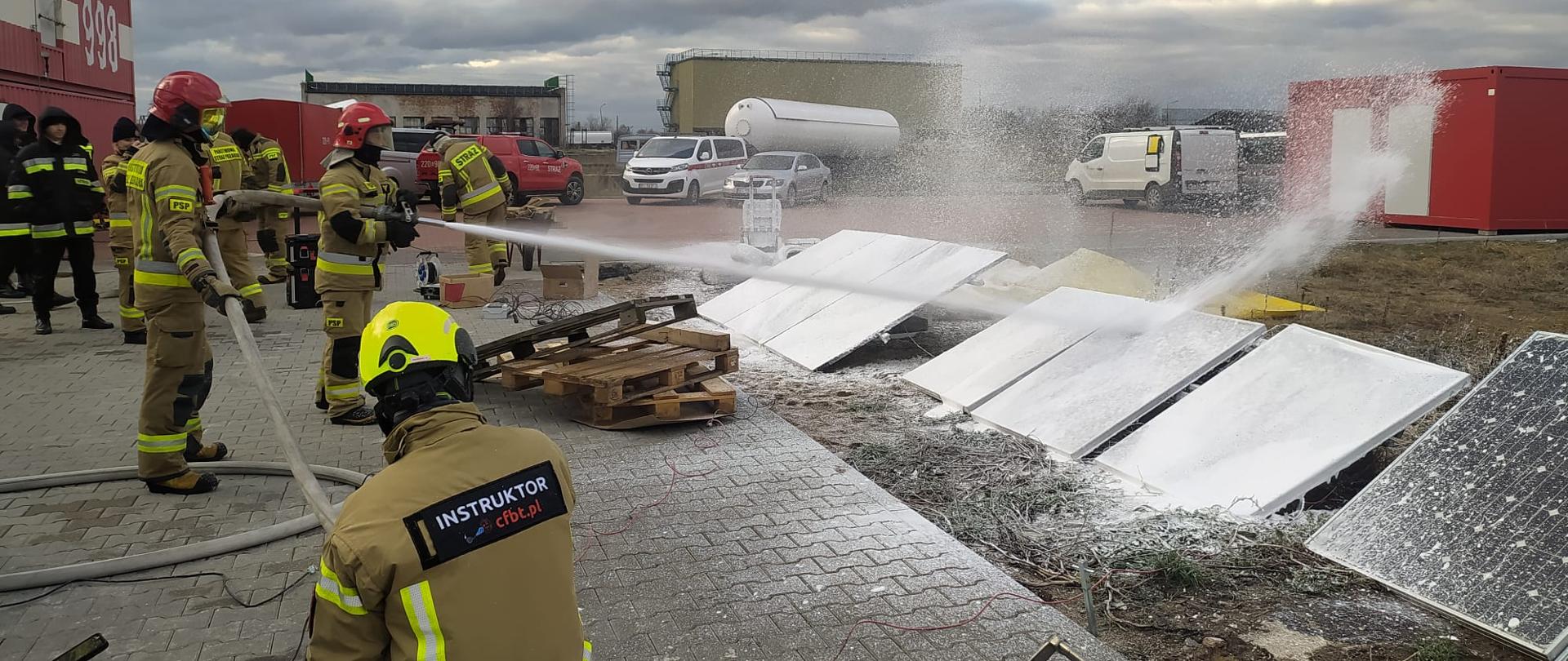 widoczni strażacy podczas podawania środka pianotwórczego na instalacje fotowoltaiczne