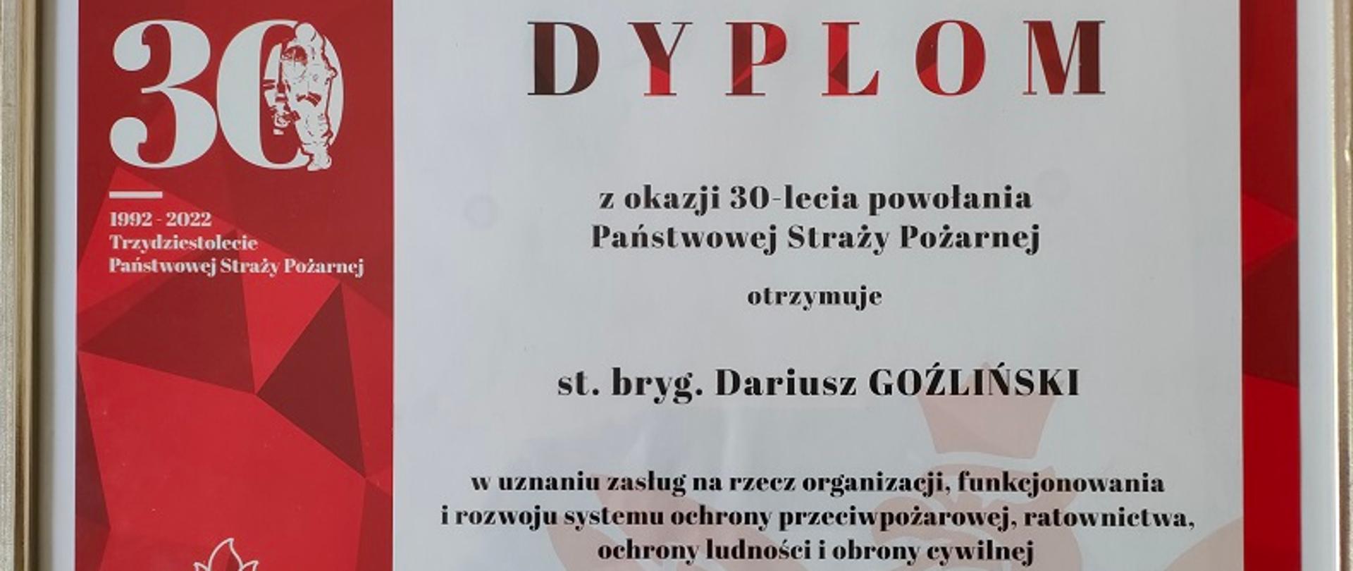 Na zdjęciu dyplom z okazji 30-lecia powołania Państwowej Straży Pożarnej dla st.bryg Dariusza Goźlińskiego Komendanta Powiatowego PSP w Tucholi. Kolorystyka dyplomu biało-czerwona w srebrnej ramie. 