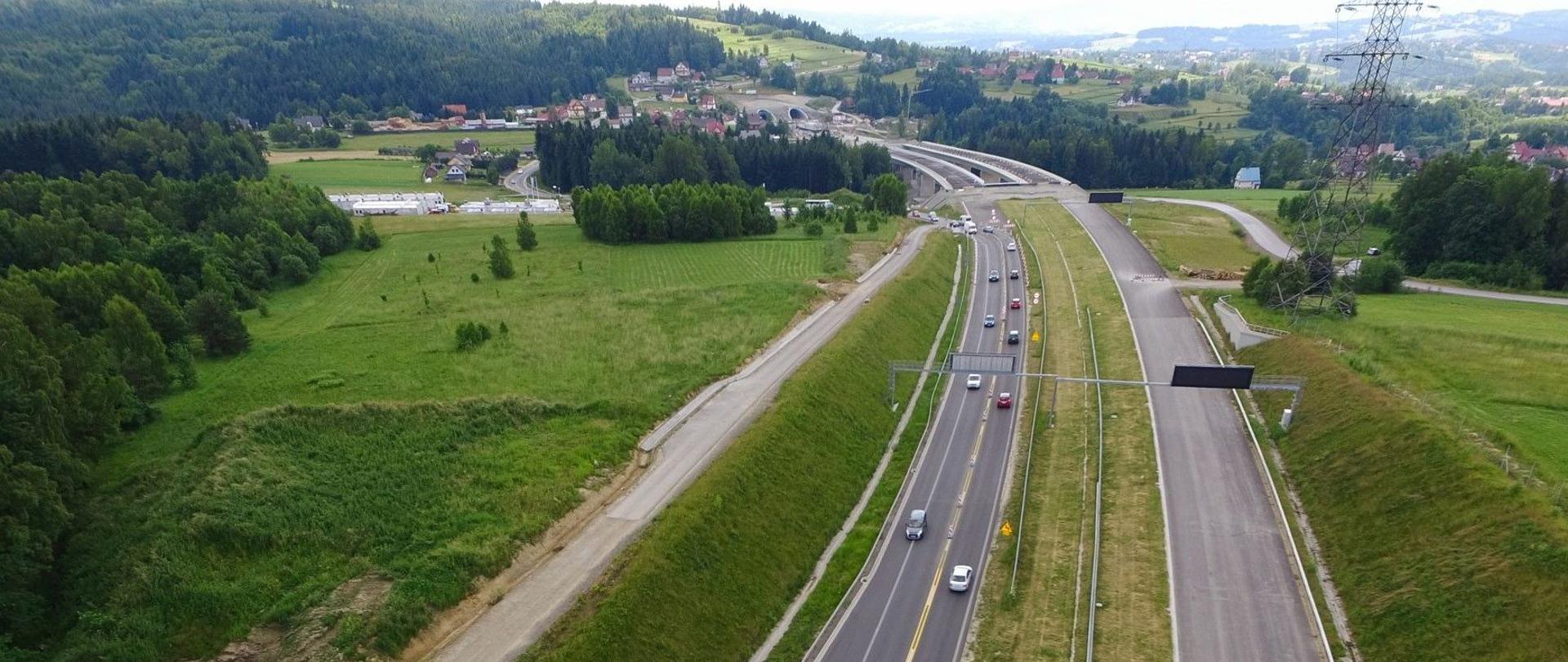 Zdjęcie przedstawia budowaną trasę S7 z widocznym mostem oraz tunelem. Ruch odbywa się jedną nitką - jeden pas wydzielony i puszczony do ruchu w kierunku budowanego mostu. W przeciwnym kierunku, wyodrębnione zostały dwa pasy ruchu.