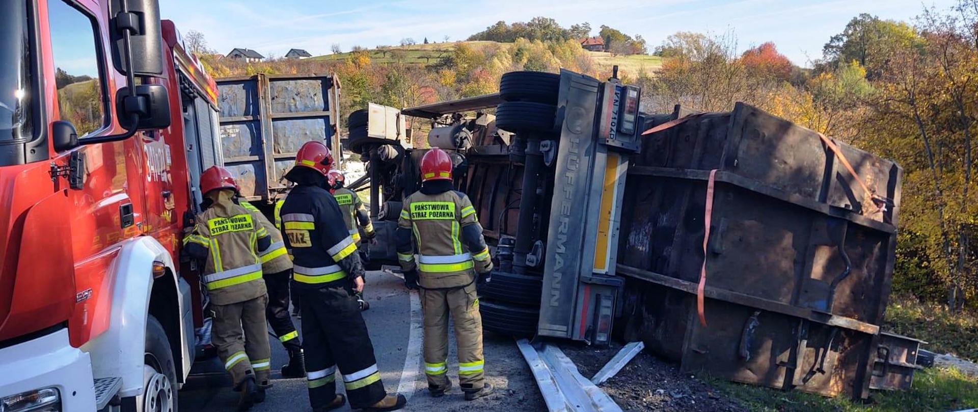Strażacy obok przewróconej przyczepy