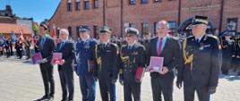 Wyróżnieni medalem z okazji trzydziestolecia Państwowej Straży Pożarnej stoją wspólnie z komendantem głównym Państwowej Straży Pożarnej oraz z pomorskim komendantem wojewódzkim Państwowej Straży Pożarnej.