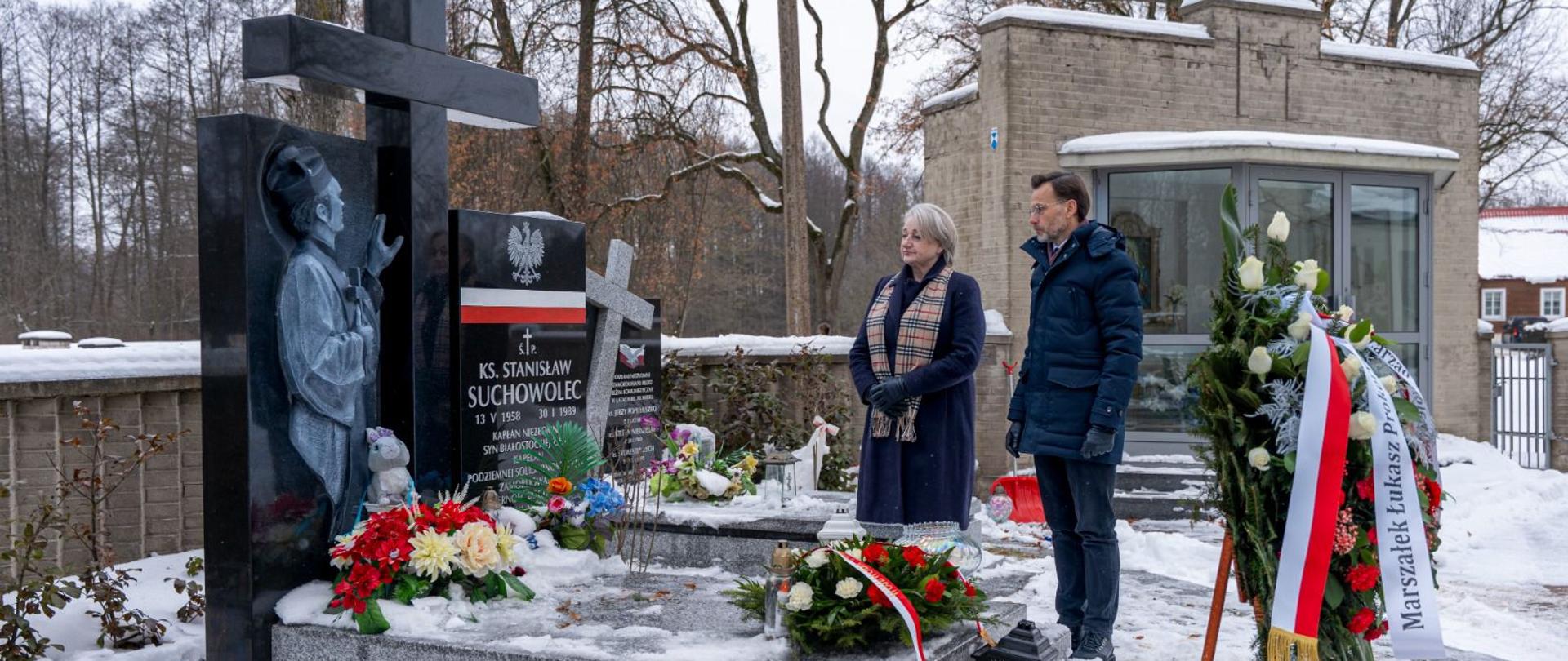Wojewoda podlaski Jacek Brzozowski w towarzystwie wicemarszałek województwa podlaskiego Wiesławy Burnos składa kwiaty na grobie księdza Stanisława Suchowolca