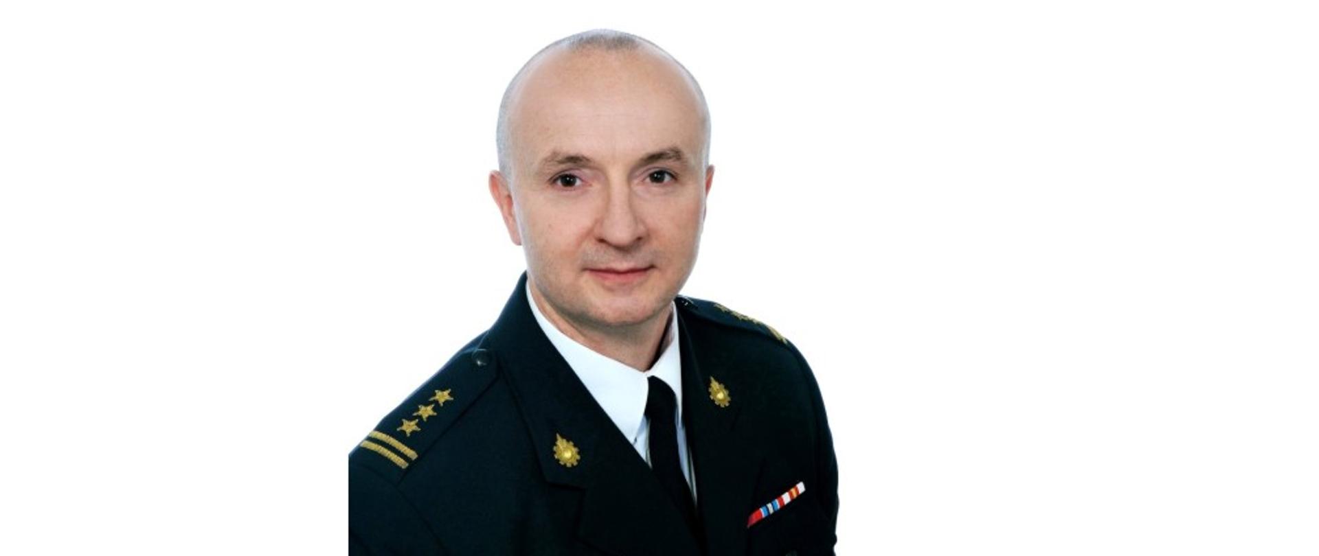 Zdjęcie przedstawia sylwetkę starszego brygadiera Zbigniewa Nowaka Zastępcy Komendanta Miejskiego Państwowej Straży Pożarnej w Krośnie, na białym tle w mundurze wyjściowym.