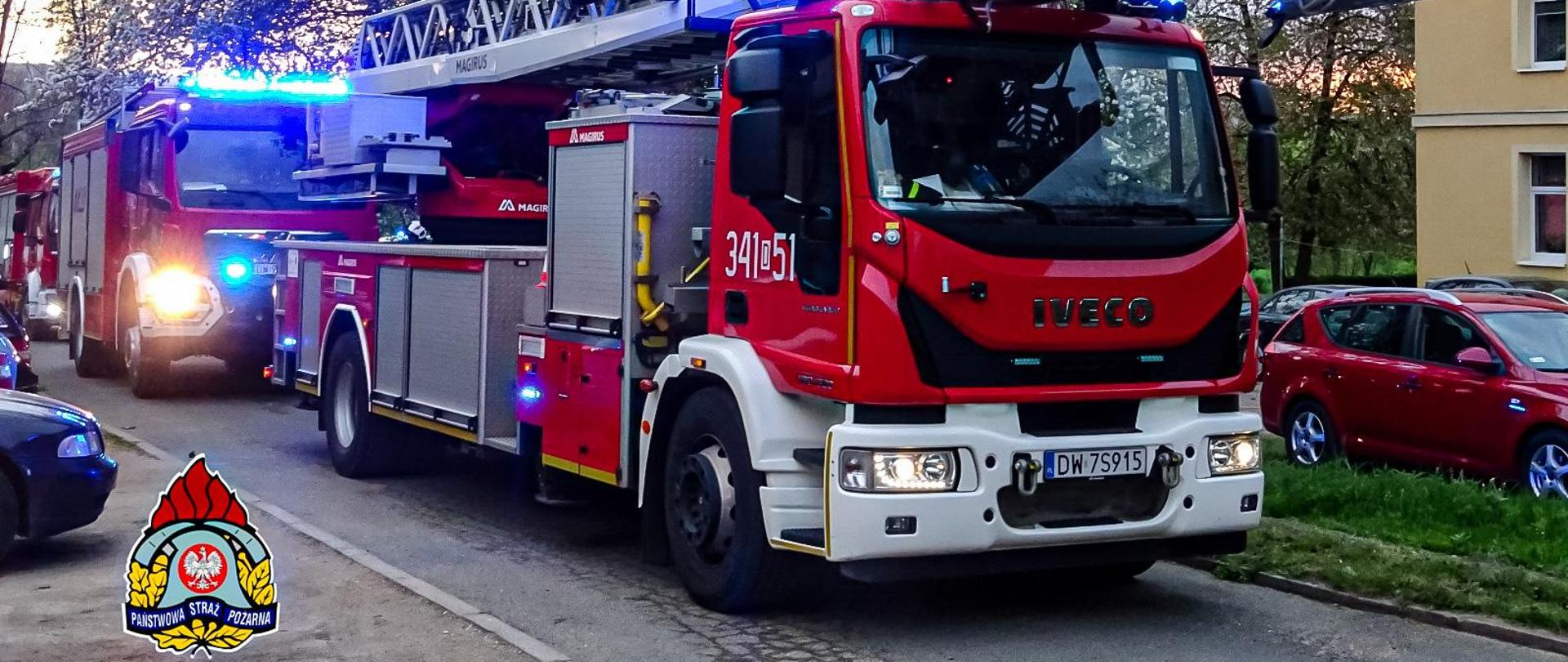 Na zdjęciu widać samochód strażacki, drabina. Samochód jest koloru czerwonego. Samochód stoi na ulicy. 