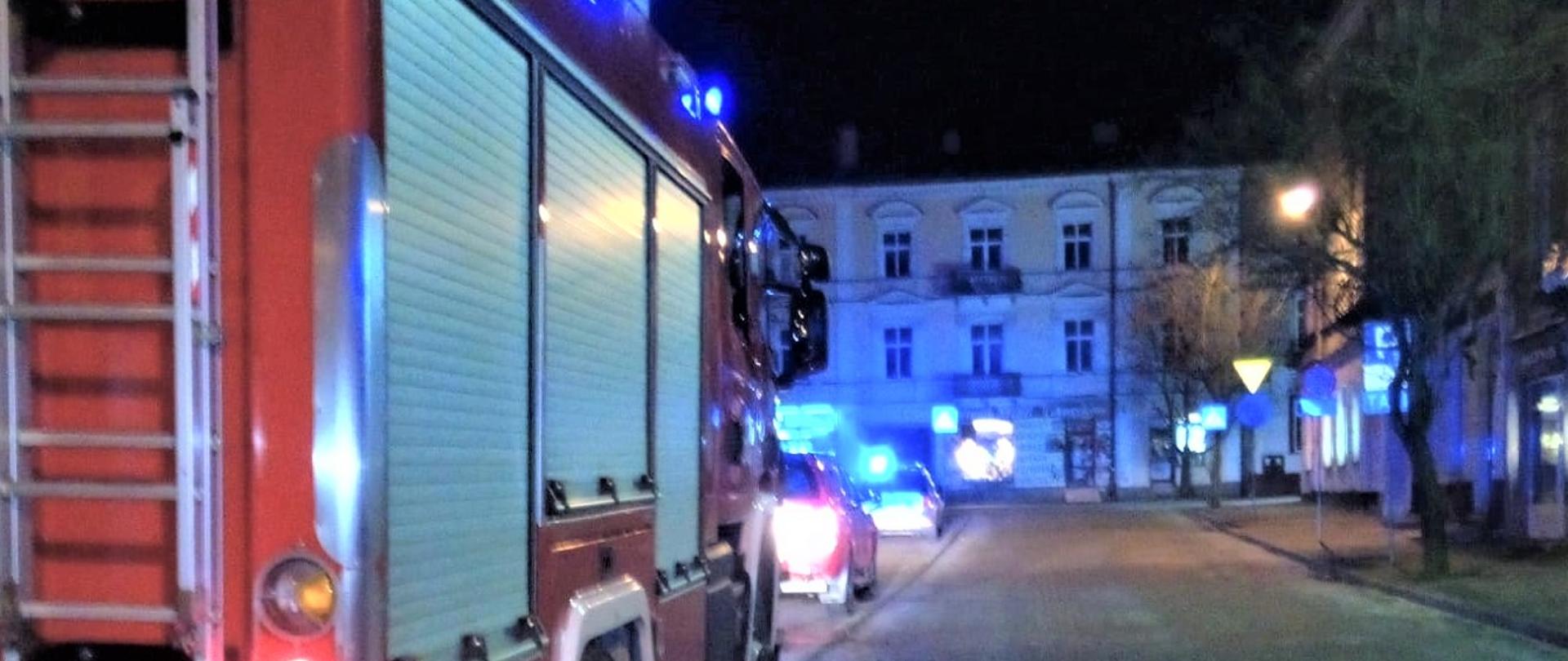 Na zdjęciu przedstawiono fragment samochodu pożarniczego biorącego udział w zdarzeniu. W perspektywie ulica biegnąca wzdłuż kamienic przy Placu Wolności w Kielcach