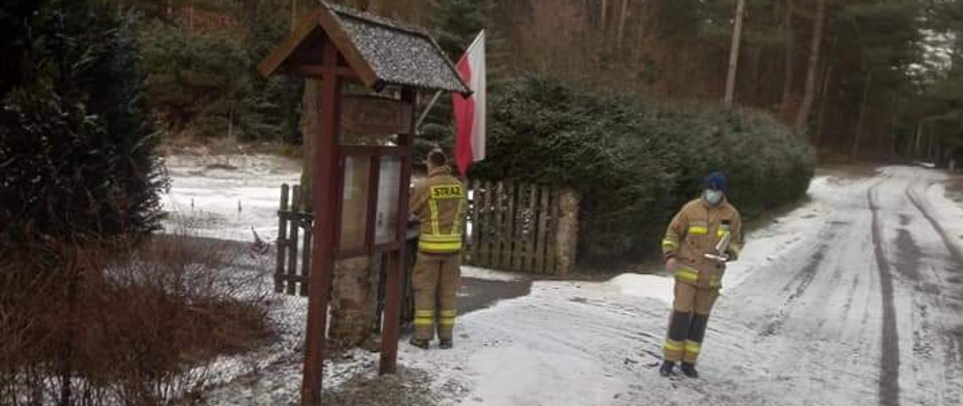 Druhowie umieszczają ulotkę w skrzynce pocztowej zabudowań