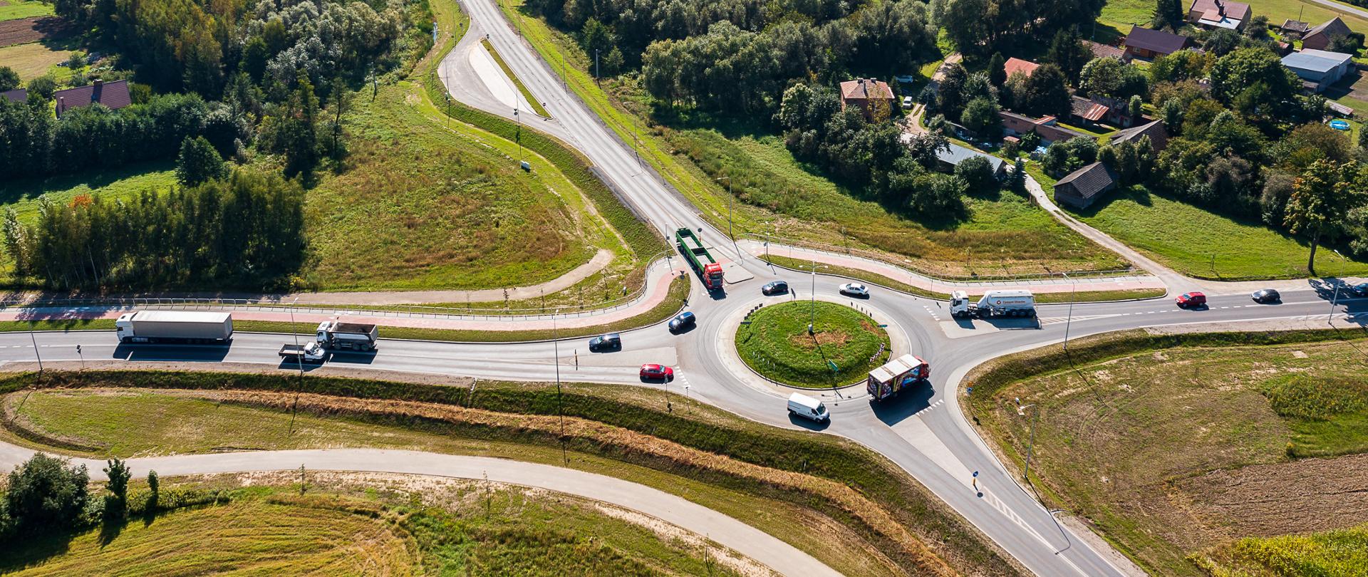 Skrzyżowanie z ruchem okrężnym, na środku rondo, jadące samochody