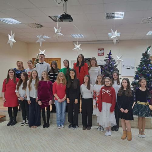 Fotorelacja z koncertu klasowego pt:"Koncert kolęd i pastorałek", który odbył się w Państwowej Szkole Muzycznej I st. w Grajewie. Przy fortepianie widać uczniów grających solo, z koleżanką lub z nauczycielką. W tle ubrane w lampki choinki, na ścianie wisi godło państwowe i portret Jana Sebastiana Bacha.