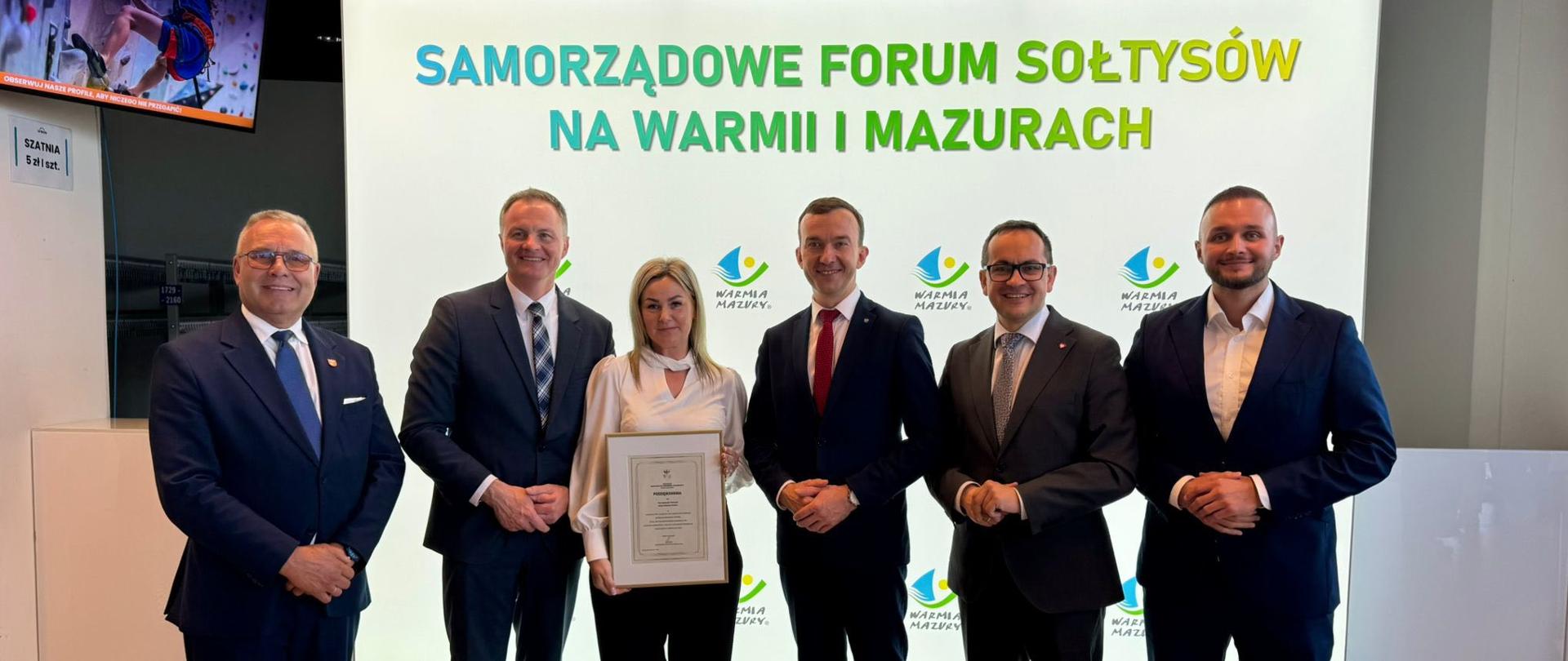 mężczyzna w garniturze, wicewojewoda, pozuje do zdjęcia z grupą ludzi 