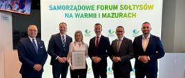 mężczyzna w garniturze, wicewojewoda, pozuje do zdjęcia z grupą ludzi 
