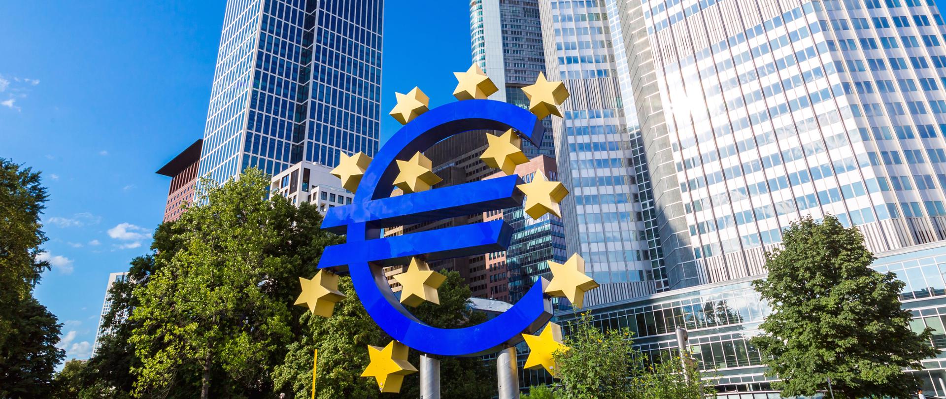 Znak euro a w tle siedziba Europejskiego Banku Inwestycyjnego we Frankfurcie nad Menem 