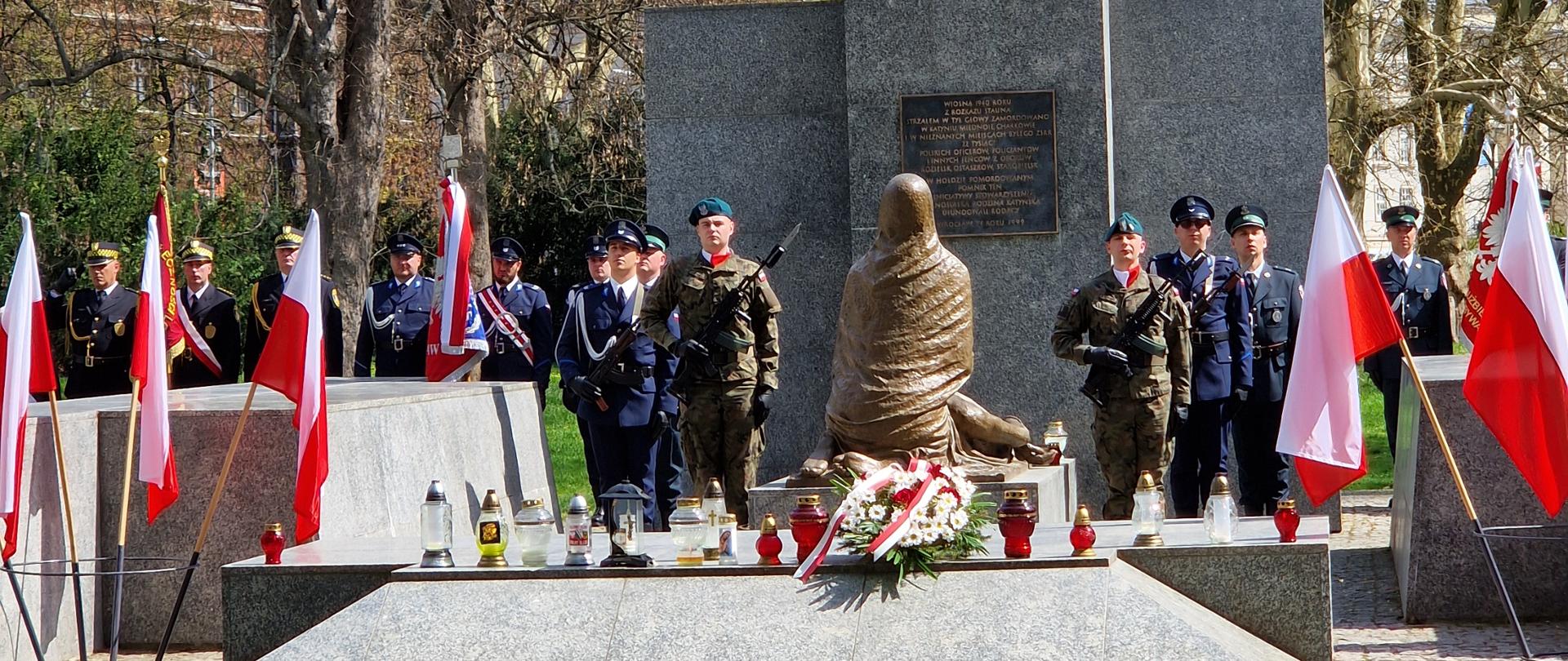 Pomnik Ofiar Zbrodni Katyńskiej we Wrocławiu. Przed pomnikiem stoją Żołnierze na warcie. Po obu stronach pomnika na stojakach umieszczono flagi Polski. 